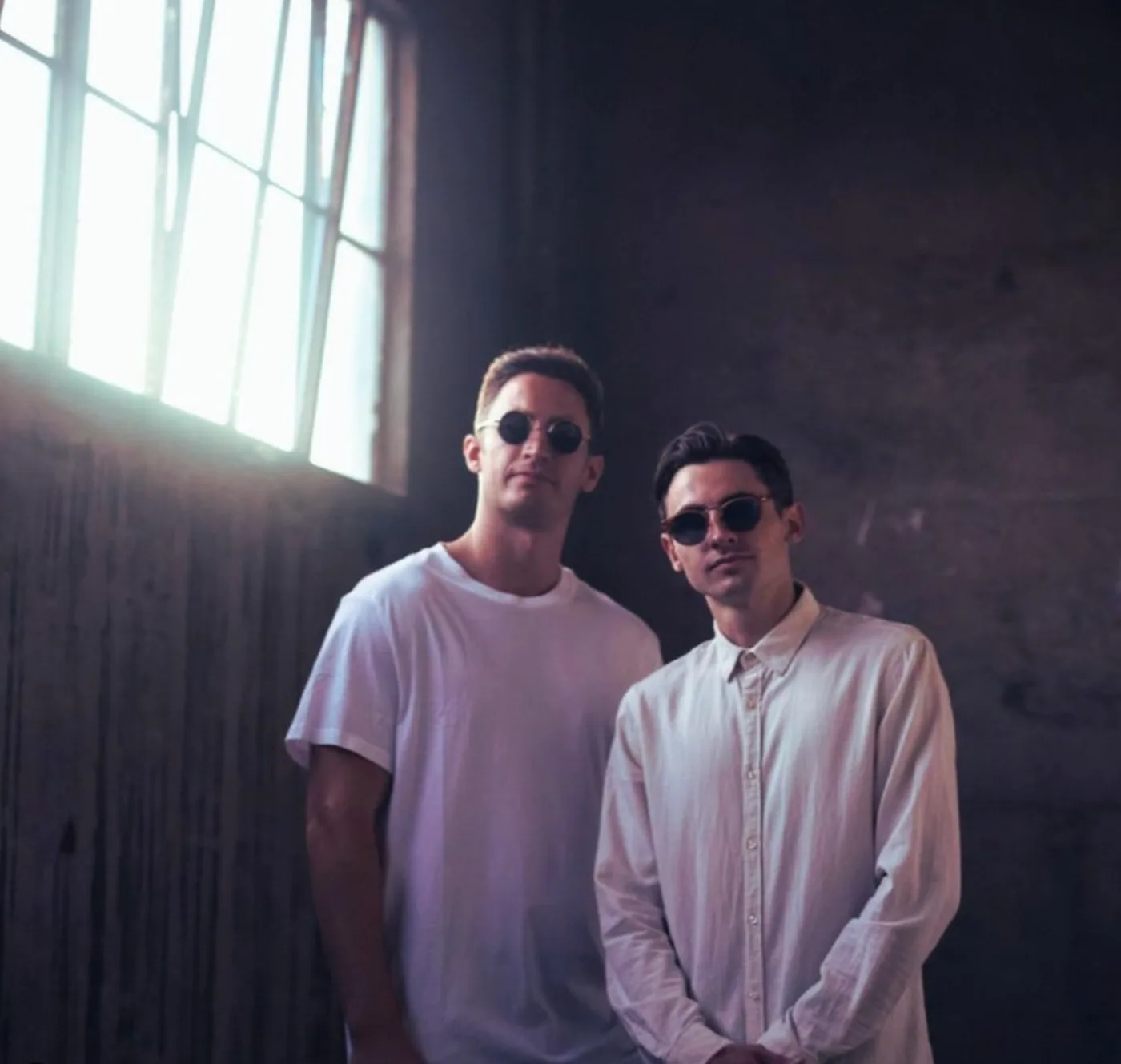 FOMO press shot of the duo standing in a warehouse with window light