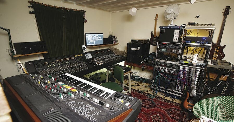 Squarepusher's studio, organized chaos with instruments and hardware in a living-room vibe