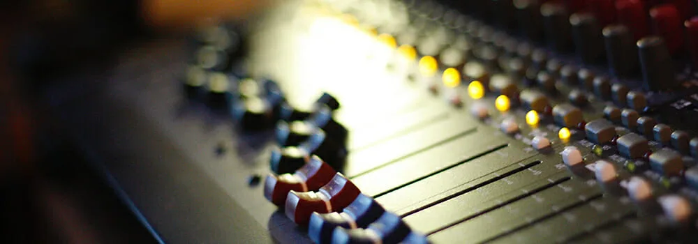 Hands on piano keys with a laptop open in a music studio setting