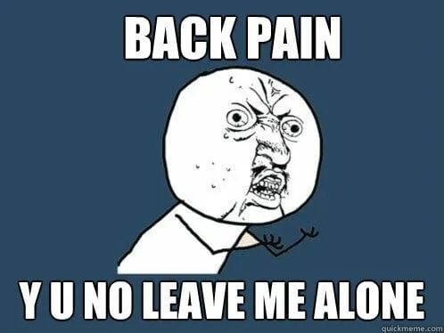 Person holding their lower back in pain while sitting at a desk