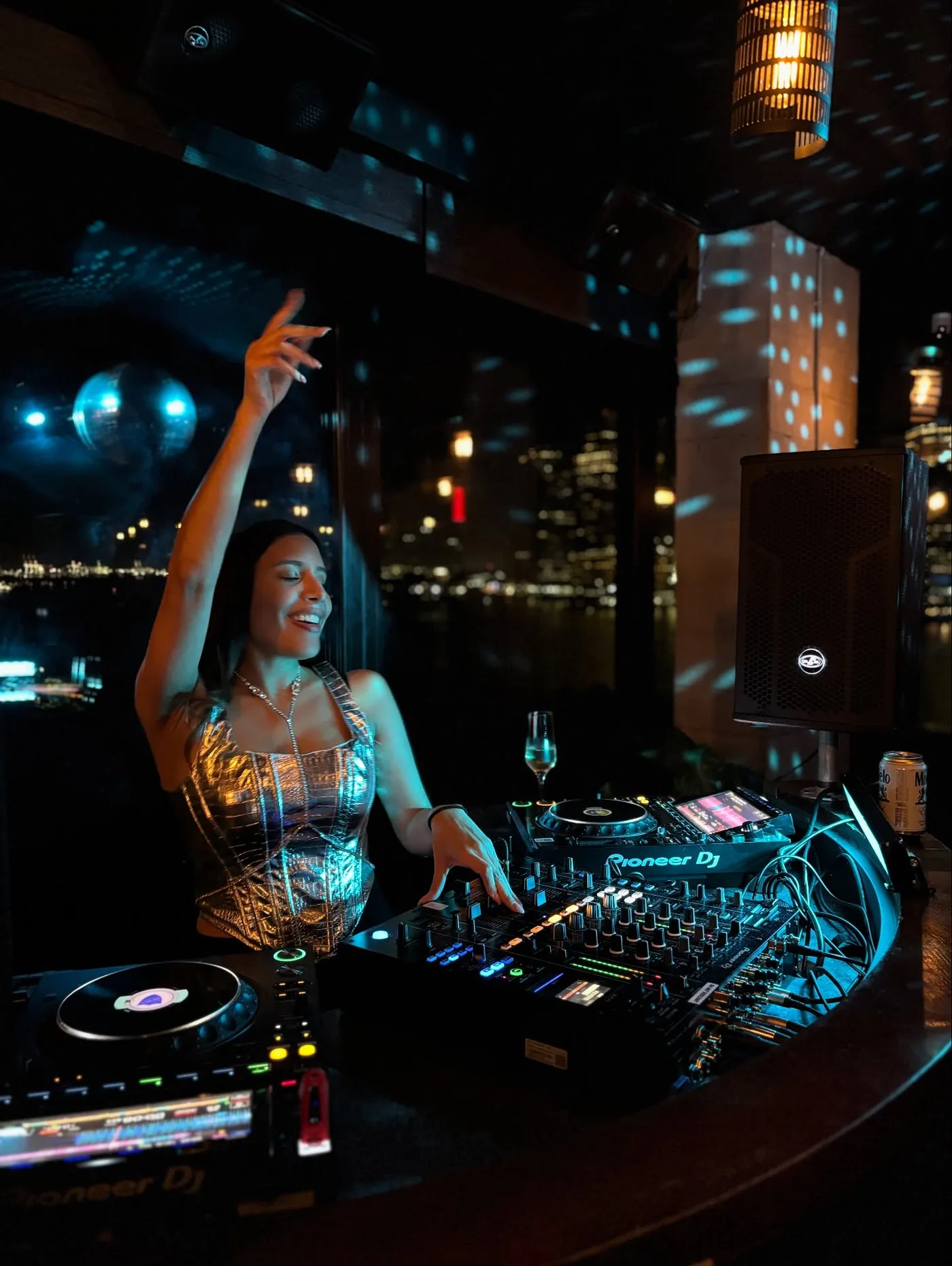 Ms. Unicorn behind Pioneer CDJs mid-set, one hand raised above the decks