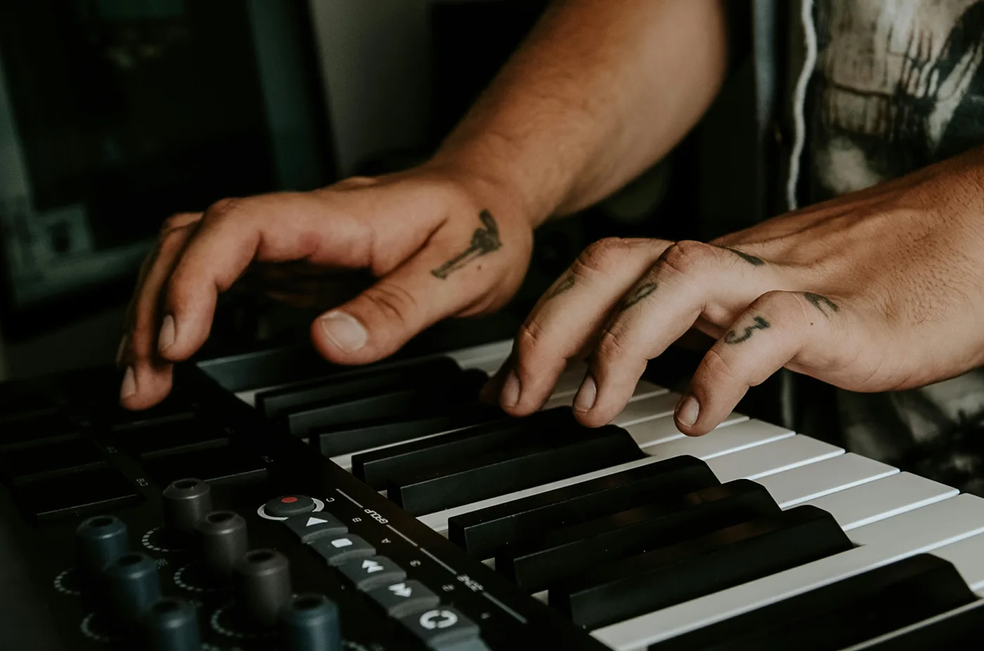 Music producer writing melodies on a MIDI keyboard in a home studio