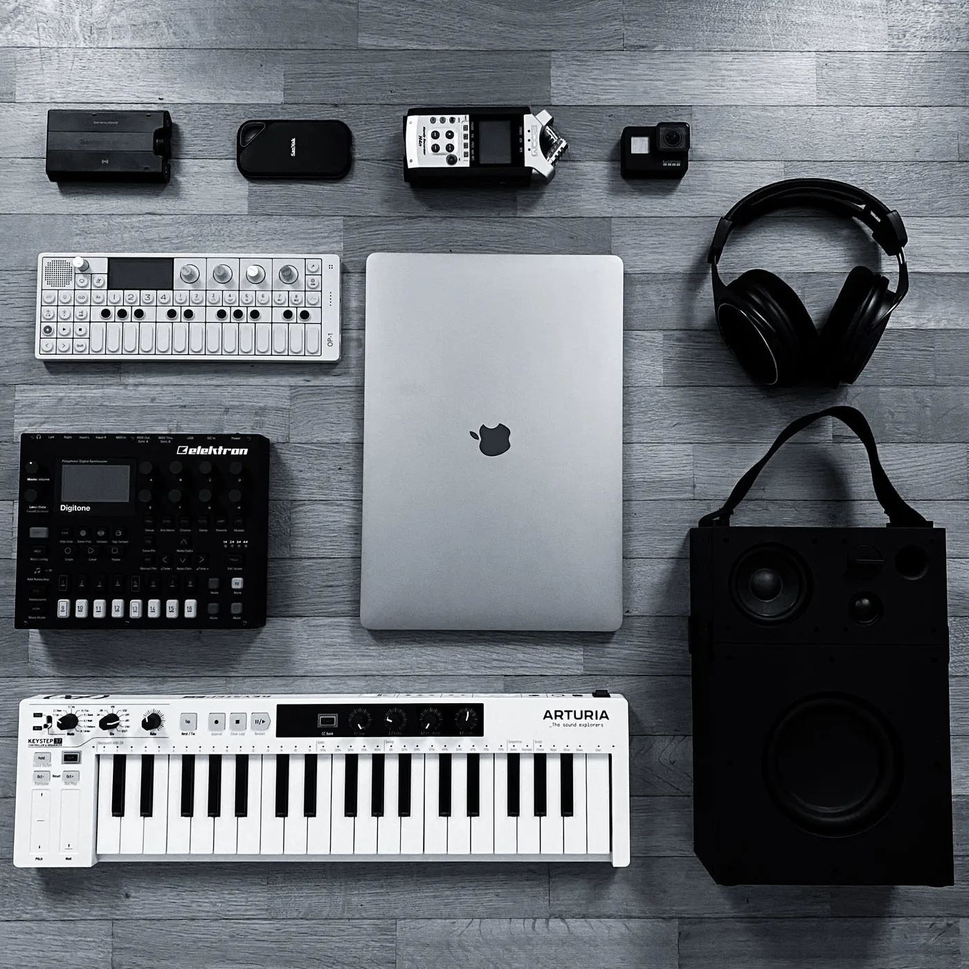 RTIK's mobile studio: a MacBook, OP-1, Digitakt, Arturia keys, and headphones laid out flat, the entire kit that travels with him from hotel to airplane to hotel