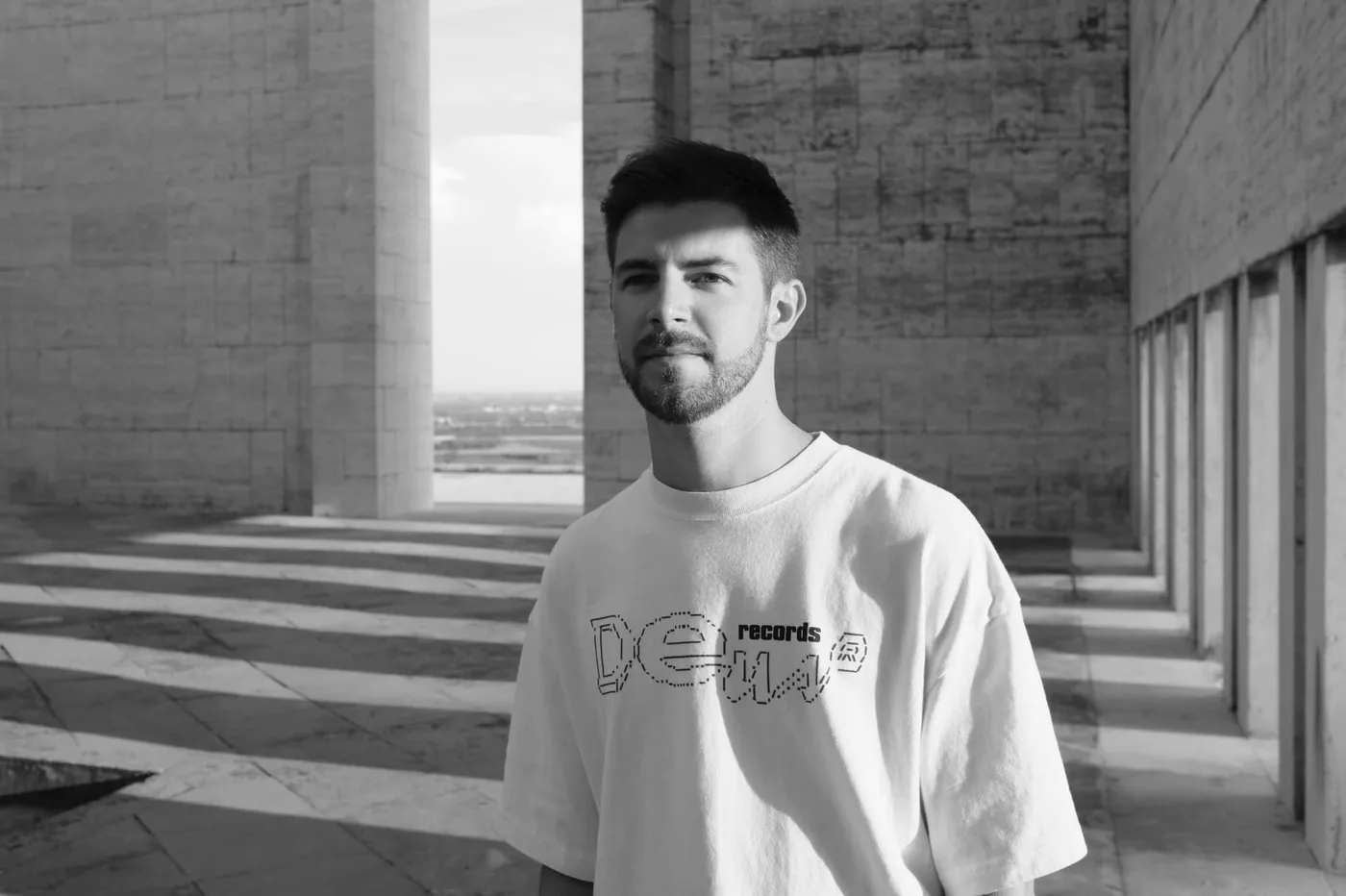 RTIK in a black and white portrait at a modernist stone monument in Italy