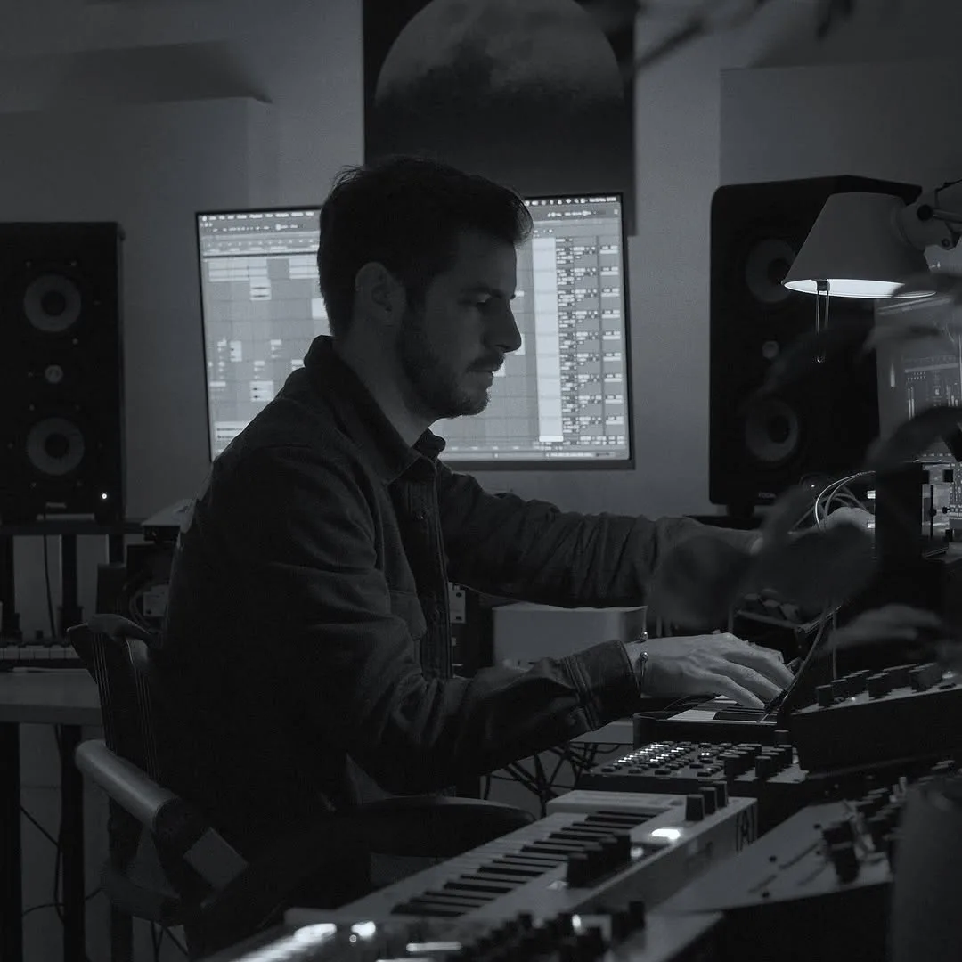 RTIK working in his home studio, Ableton on the monitor surrounded by hardware synths and studio monitors