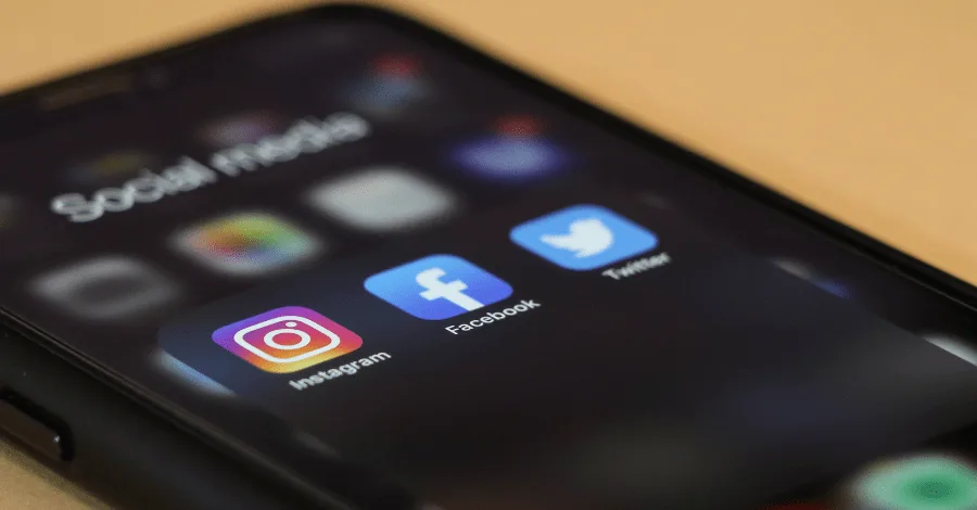Phone showing Instagram, Facebook, and Twitter app icons stacked on a home screen
