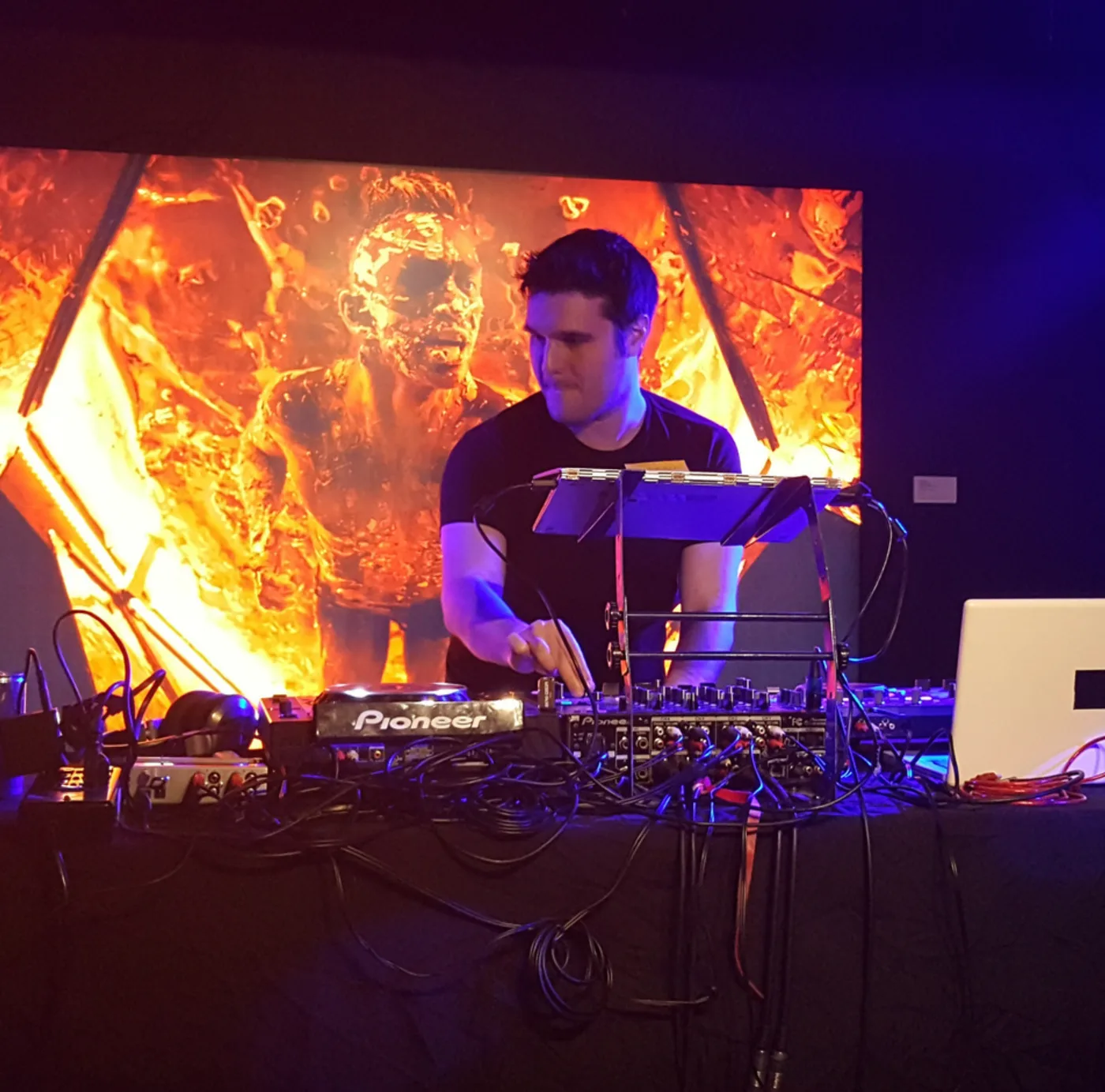 Tom Rogers mixing live in front of a fiery Castle of False Light visual backdrop