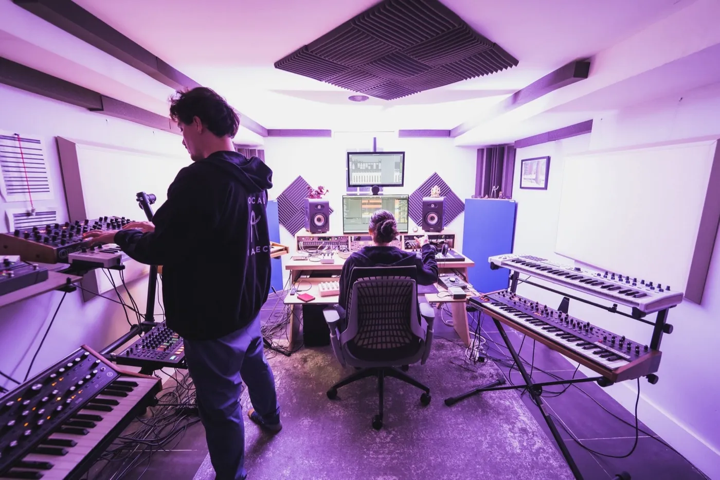 Local Dialect working together in their studio, surrounded by synths